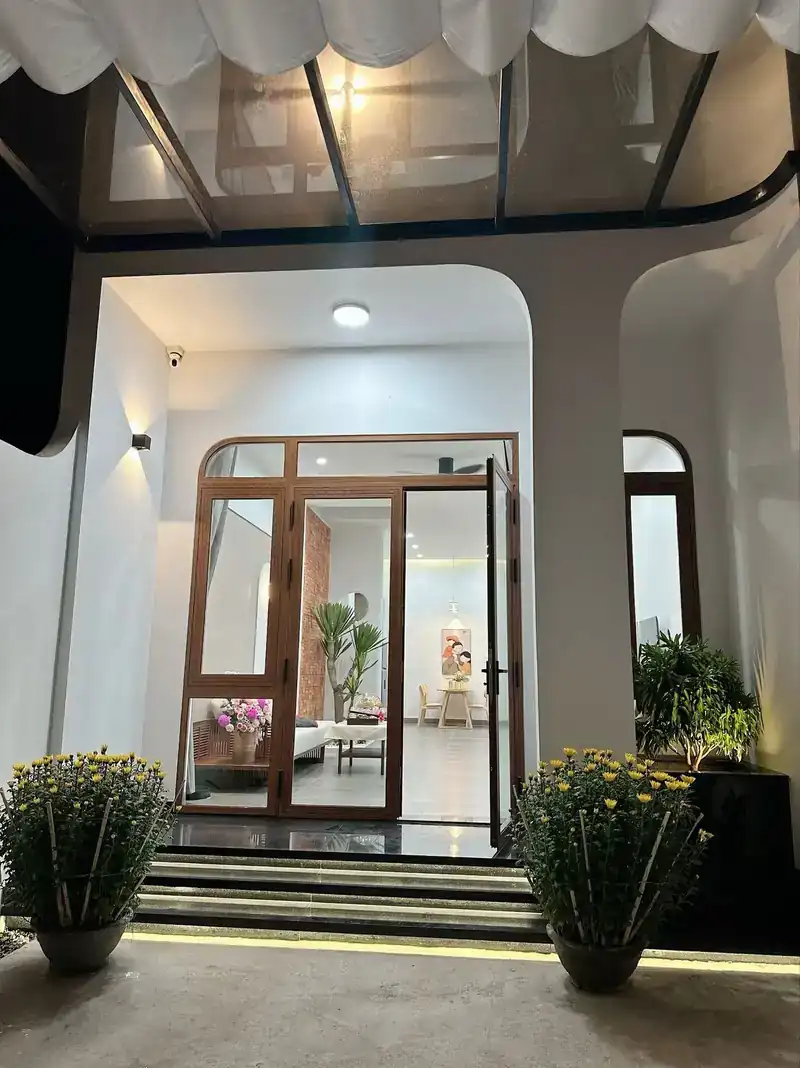 Cửa vòm gỗ kính nhà cấp 4 Kon Tum — hiên B-House, hoa cúc, bậc đá