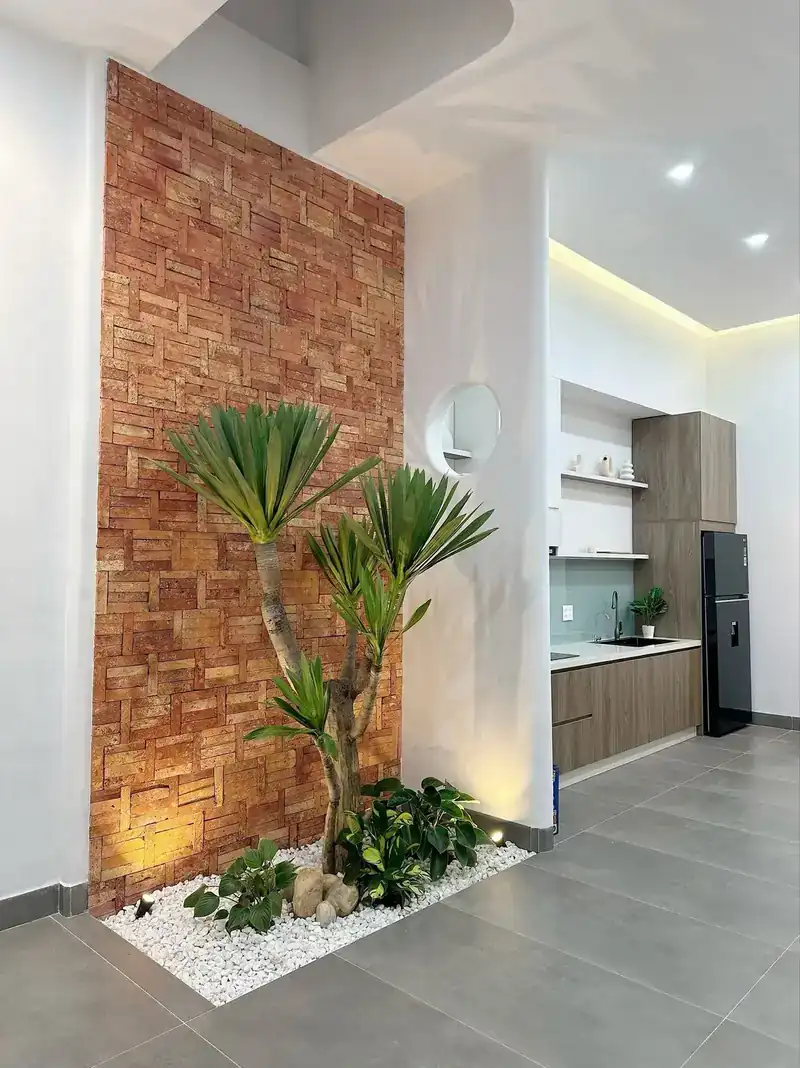 Vườn gạch thẻ trong nhà cấp 4 Kon Tum — cây, sỏi trắng, ô tròn nhìn bếp, B-House