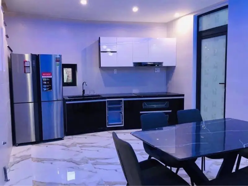 Bếp nhà phố 2 tầng CP-House Kon Tum — tủ dưới đen tủ trên trắng, tủ lạnh, bàn ăn đá