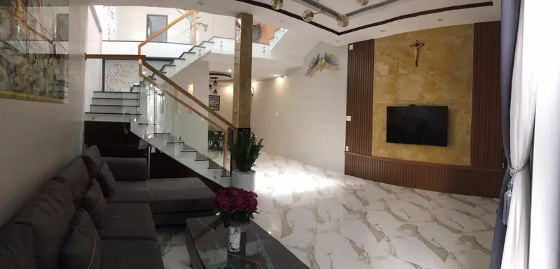 Phòng khách và cầu thang kính nhà phố 2 tầng Kon Tum — thông tầng, sàn đá, CP-House đã hoàn thiện
