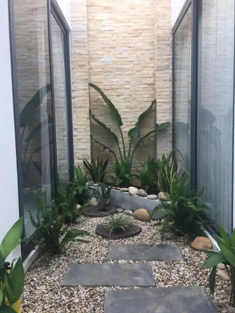 Sân trong nhà cấp 4 phố Kon Tum — đá ốp, sỏi, dương xỉ, cửa kính, HQ-House