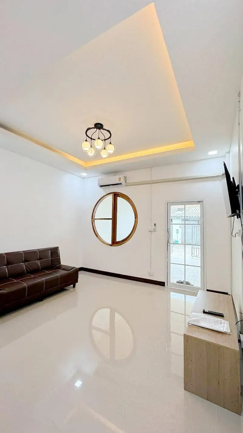 Phòng khách nhà cấp 4 MN-House Kon Tum — sofa nâu, cửa sổ tròn, trần hắt LED sau sửa nhà