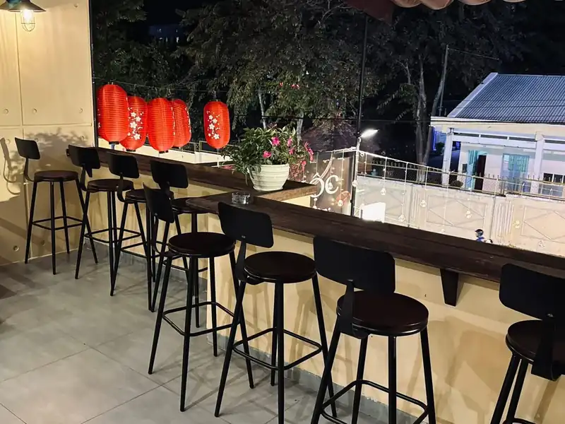 Sân thượng Mộc Cafe Kon Tum — quầy bar gỗ, ghế đẩu, nhìn ra cây hàng xóm