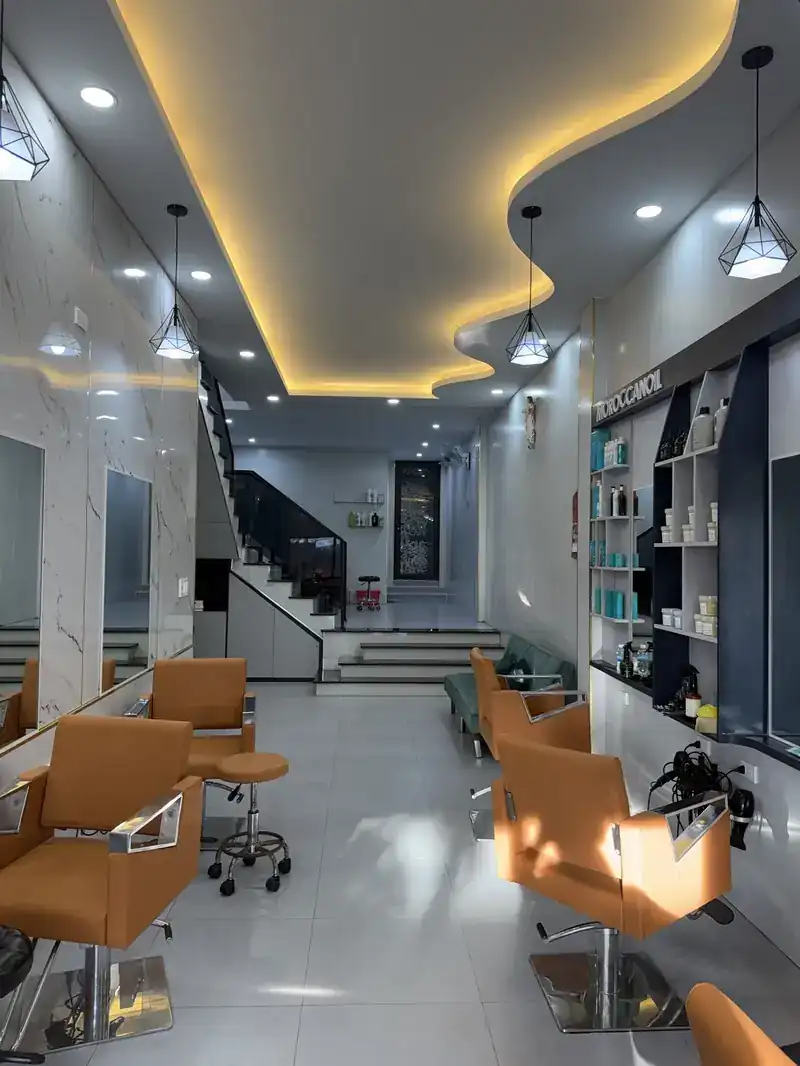 Bên trong salon tóc Kon Tum — ghế cam, gương, trần hắt LED, nhà phố kết hợp kinh doanh